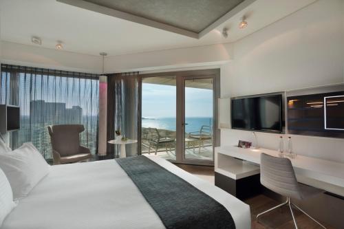 a bedroom with a bed and a desk with a television at Royal Beach Hotel Tel Aviv by Isrotel Exclusive in Tel Aviv