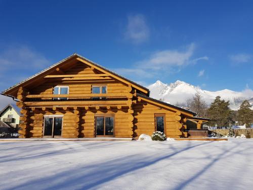 a log cabin in the snow with mountains in the background at Vysoké tatry - Tatranská Lomnica - zrub,drevenica in Tatranská Lomnica