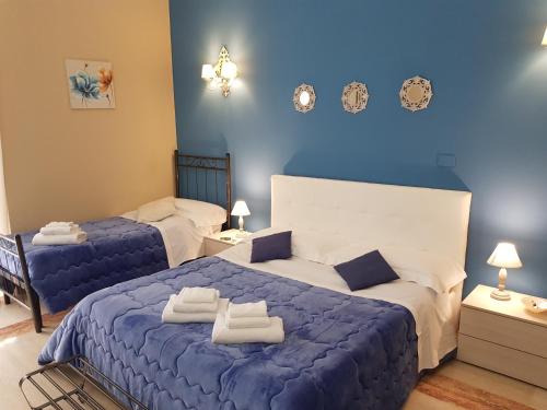 a bedroom with two beds and a blue wall at B&B Sicily Luxury in Catania