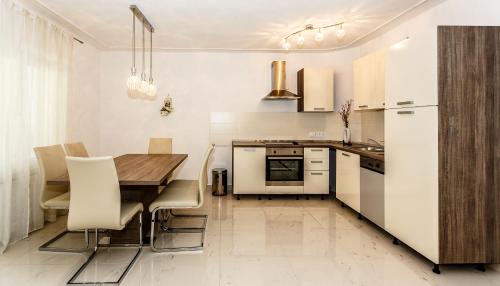 kuchnia z drewnianym stołem i białymi urządzeniami w obiekcie Sara Apartments Malinska w mieście Malinska