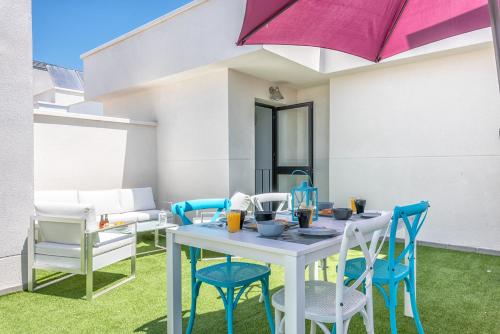 un patio con mesa, sillas y sombrilla en Atico terraza privada piscina centro ac nuevo 1hab, en Málaga