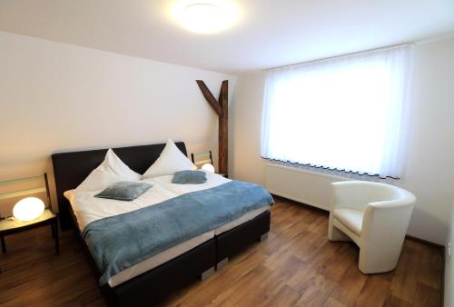a bedroom with a bed and a window and a chair at Villa Rynek in Góra Świętej Anny