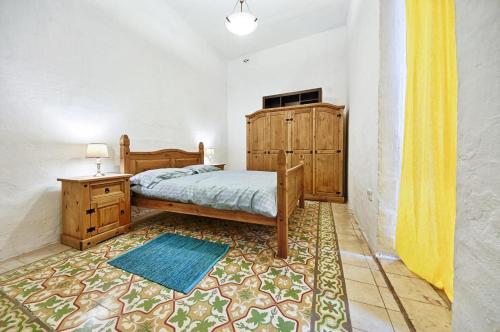 a bedroom with a bed and a cabinet and a rug at Valletta Heritage Town House in Valletta