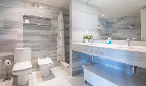 a bathroom with a toilet and two sinks and a mirror at You Stylish Beach Apartments in Barcelona