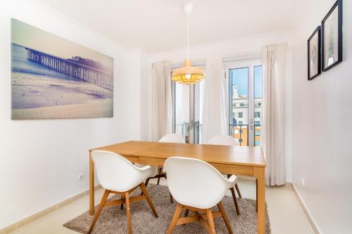 a dining room with a wooden table and white chairs at LXLUXHOME - Casino Premium Apartment in Lisbon