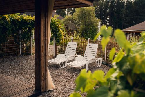 three white chairs sitting under a gazebo at Leśna Oaza in Borek