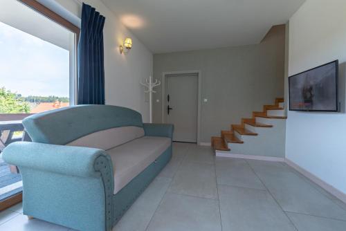 a living room with a blue couch and a staircase at Malinowe Wzgórze domki 90 m2 z sauną i balią in Krzeszna