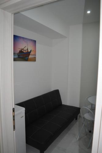 a black couch in a room with a painting on the wall at P.L Hermes Studios & Apartments in Larnaka