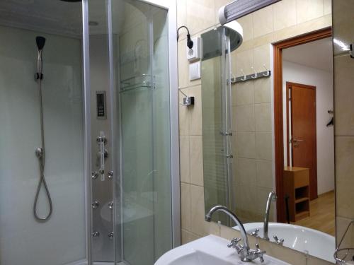 y baño con ducha acristalada y lavamanos. en Acopark Vendégház en Debrecen