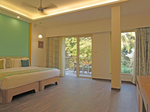 a bedroom with a bed and a balcony at Acron Seaway Resort in Candolim