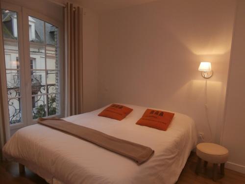 1 dormitorio con 1 cama con 2 almohadas de color naranja en au Claire de lune, en Dieppe
