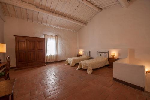 two beds in a large room with a window at Certosa di Pontignano Residenza d'Epoca - Place of Charme in Ponte A Bozzone