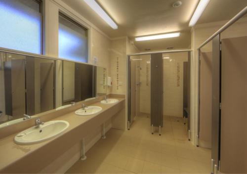 a bathroom with three sinks and stalls with mirrors at Kosciusko Tourist Park in Jindabyne