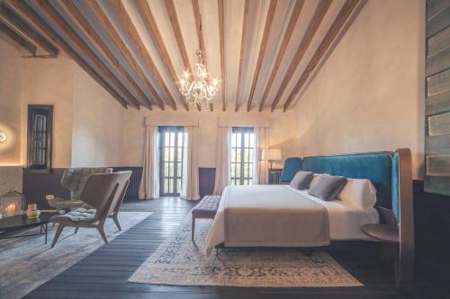 a bedroom with a bed and chairs and a chandelier at Can Bordoy Grand House Hotel GL Preferred Hotel in Palma de Mallorca