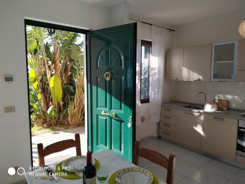 een groene deur die leidt naar een keuken met een tafel en een tafel bij Giardino Miramare CITRA zero zero ottanta trentuno LT 0737 in Imperia