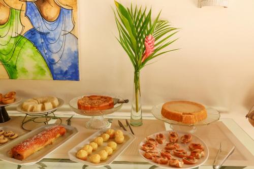 a table topped with plates of food and a vase at Pousada Coisa e Tao in Arraial d'Ajuda