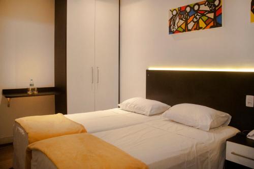 a bedroom with two beds and a painting on the wall at Bras Palace Hotel in Sao Paulo