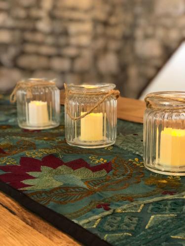 three votive candles in glass jars on a table at Historic Grade II Listed Homely Cottage in Stamford