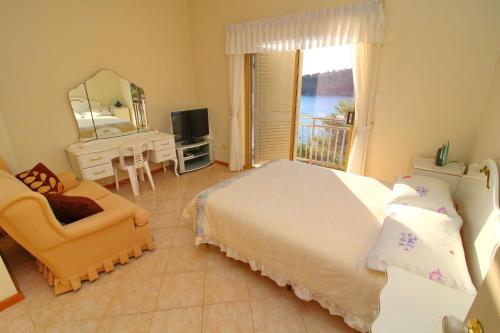 a bedroom with a bed and a chair and a window at Apartments Villa Steffi in Prizba