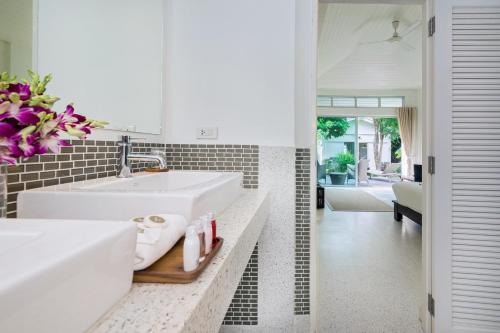 a white bathroom with a sink and a living room at Ban Mok Talay Beachfront Villa in Bang Rak Beach