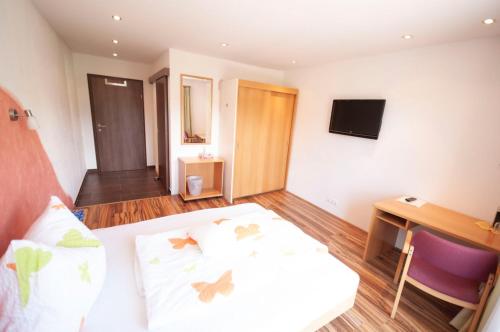 Dormitorio con cama, escritorio y TV en Gasthof Winkelwirt, en Althofen