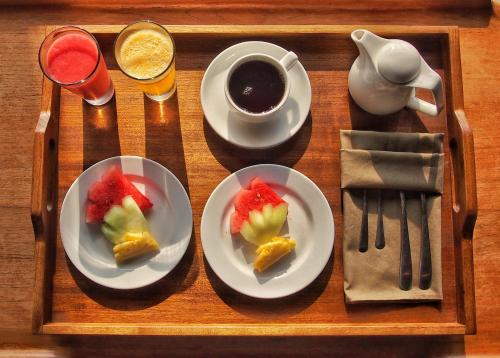 a tray with two plates of fruit and a cup of coffee at Villa So Long Banyuwangi - Ijen in Banyuwangi