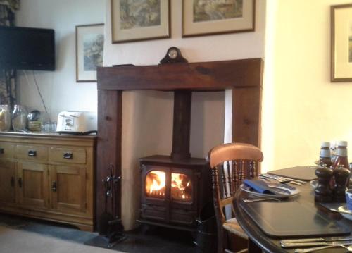 a woodburning stove in a dining room with a table at Holmeshead Farm in Ambleside