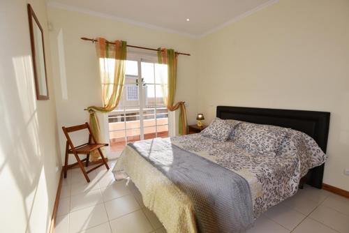 1 dormitorio con cama, ventana y silla en 12 A Clube Golfemar, en Carvoeiro