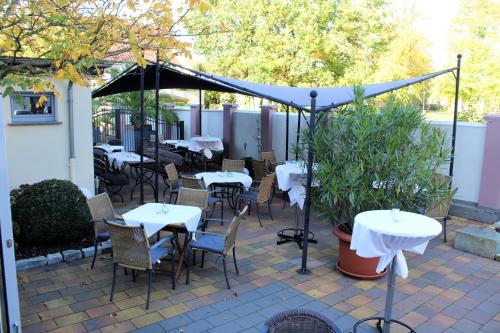 eine Terrasse mit Tischen und Stühlen unter einem Baldachin in der Unterkunft Hotel-Restaurant Sälzerhof in Salzkotten