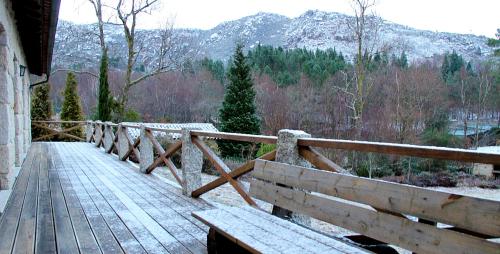 a wooden walkway with a wooden fence and snow covered mountains at Casa Natura Gerês in Campo do Gerês