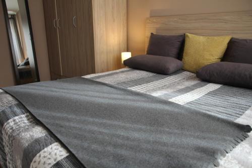 um quarto com uma cama grande com almofadas cinzentas e amarelas em Apartment 46 em Sófia