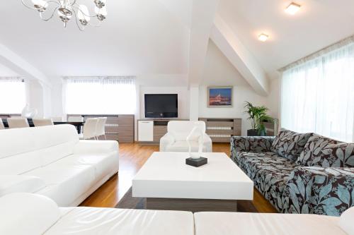 a living room with white furniture and a flat screen tv at Garni Hotel Nevski in Belgrade