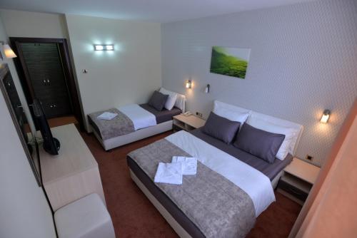 a hotel room with two beds and a couch at Hotel Livade in Čačak
