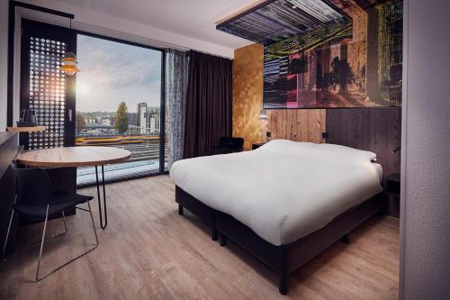 a bedroom with a bed and a table and a window at Inntel Hotels Utrecht Centre in Utrecht