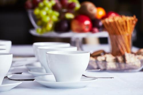 a table with white cups and a bowl of fruit at Hotel Smile Pieniny in Szczawnica