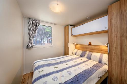 a small bedroom with a bed and a window at Albatross Mobile Homes on Camping Mare e Pineta in Lido degli Estensi