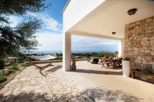 a patio with a table and a stone wall at Le Gioie - Villa Macchia Mediterranea - Splendida villa vista mare immersa nel verde in Torre Pali 