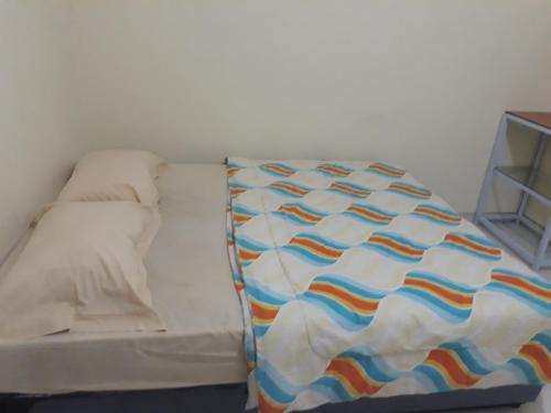 a bed with a colorful blanket on top of it at Jakson Homestay in Batam Center