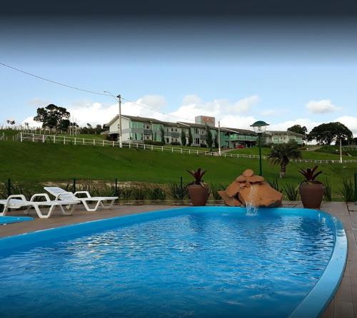 einen Pool mit zwei Stühlen und ein Haus in der Unterkunft Hotel Ecovilly in Santo Antônio