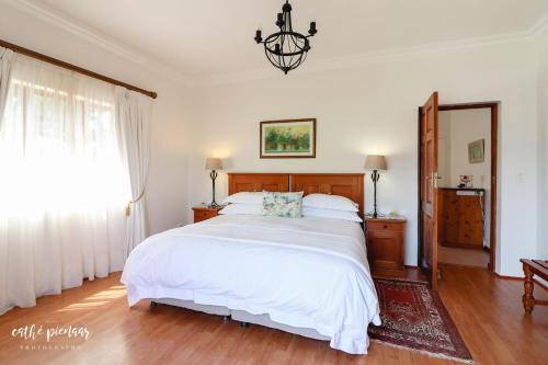 a bedroom with a large white bed and a chandelier at A Tuscan Villa Guest House in Fish hoek