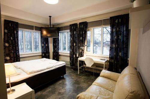 a bedroom with a bed and a couch and windows at Hotel CityHovi in Rauma