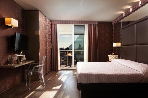 a hotel room with a bed and a view of a balcony at Hotel Kristal Palace - TonelliHotels in Riva del Garda