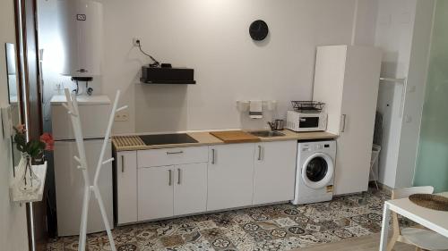 Biała kuchnia z pralką i pralką w obiekcie Suites Jeronimo de Cordoba w Sewilli