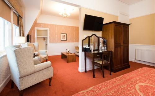 a living room with a tv and a couch and a chair at The Atholl Palace in Pitlochry