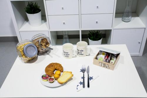 einen Tisch mit einem Teller Essen und zwei Tassen in der Unterkunft Carretería Center Apartments in Málaga