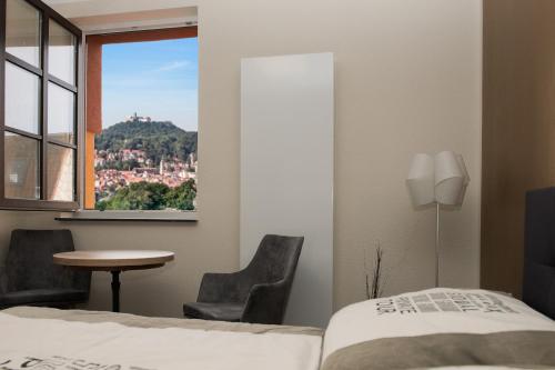 a bedroom with a bed and a table and a window at Hostel & Pension Alte Brauerei in Eisenach