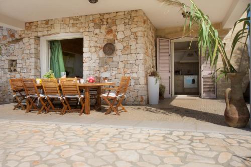 a stone house with a wooden table and chairs at Le Gioie - Villa Macchia Mediterranea - Splendida villa vista mare immersa nel verde in Torre Pali 