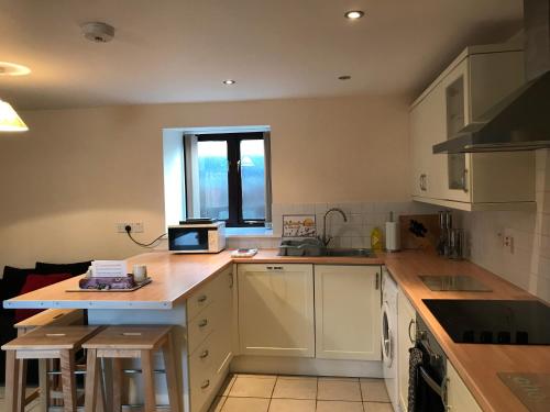 a kitchen with white cabinets and a counter top at Sedbury Farm Cottages in Chepstow