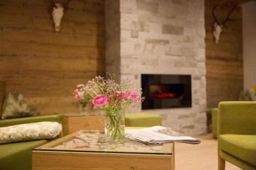 a vase of flowers on a table in a living room at Hotel Grüner Baum in Zell am See