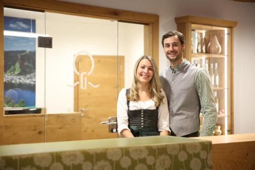 a man and a woman standing next to a table at Hotel Grüner Baum in Zell am See